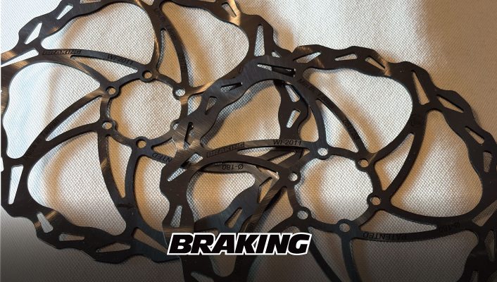 BRAKINGのロゴが入った、2枚の重なり合ったブラックメタル製の自転車用ディスクブレーキローター。.
